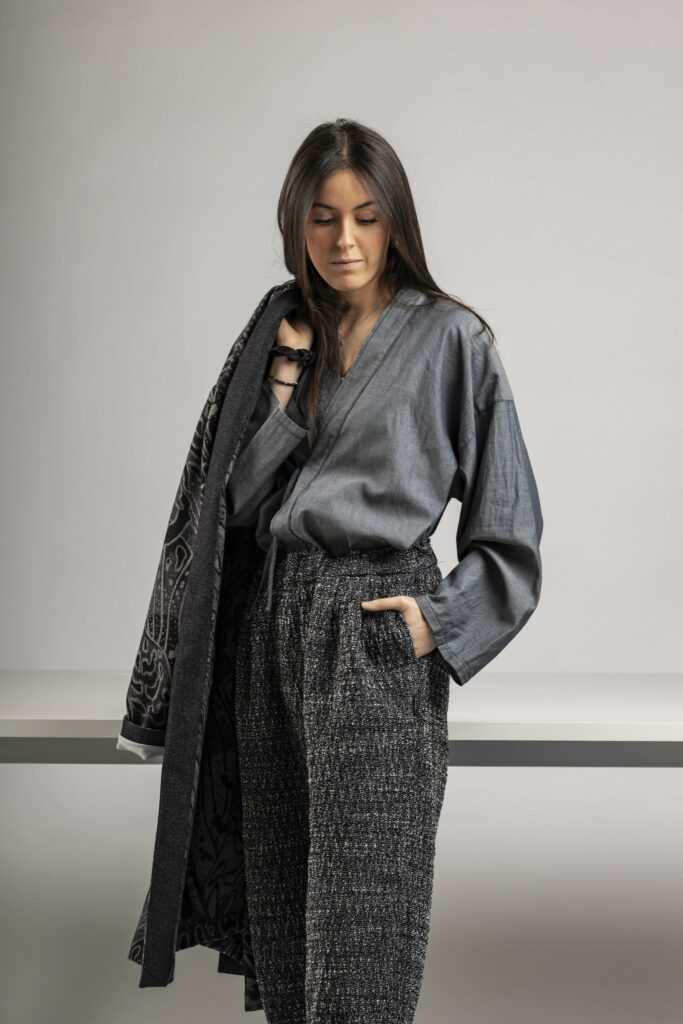 Camicia Kimono con chiusura frontale a laccio. Tessuto in cotone leggero tinto indaco. Pantaloni in lana cotone, fantasia geometrica herringbone nera e bianca.